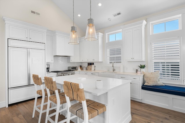 kitchen featuring white cabinets, paneled built in fridge, sink, and a center island