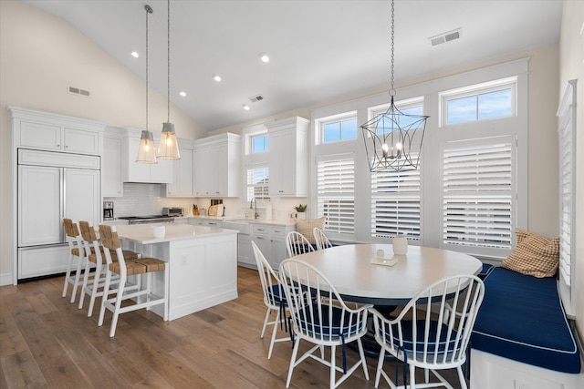 dining room featuring sink, high vaulted ceiling, a chandelier, and dark hardwood / wood-style floors