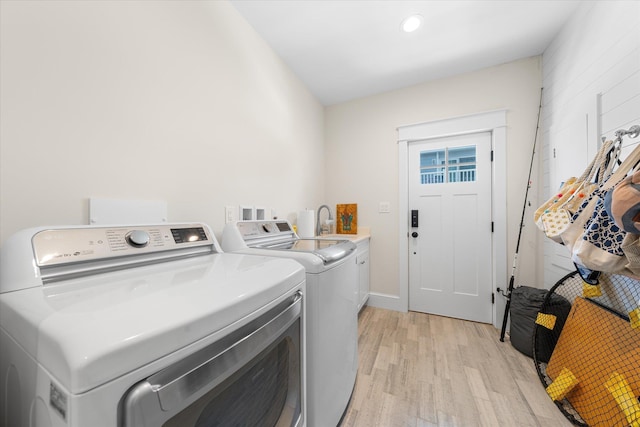 laundry area with cabinets, light hardwood / wood-style flooring, and washing machine and clothes dryer