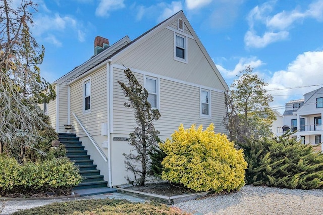 view of side of property with stairway and a chimney