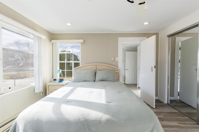 bedroom featuring hardwood / wood-style flooring, baseboard heating, and a closet