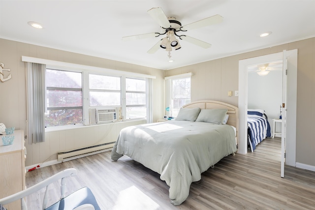 bedroom with ceiling fan, cooling unit, a baseboard radiator, and light hardwood / wood-style floors