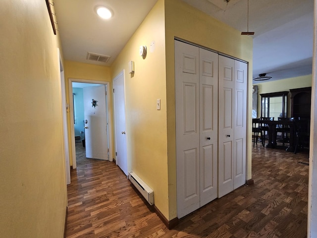 hallway featuring visible vents, baseboard heating, and dark wood finished floors