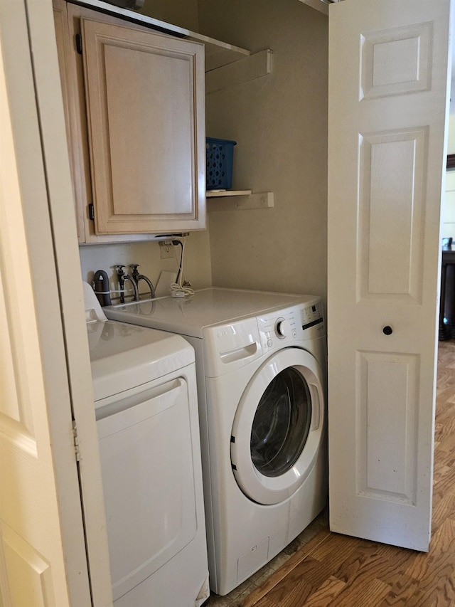 laundry room featuring washer and clothes dryer, cabinet space, and wood finished floors