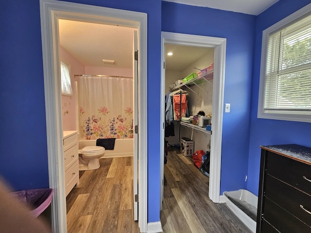 bathroom featuring shower / bath combo, vanity, toilet, baseboards, and wood finished floors