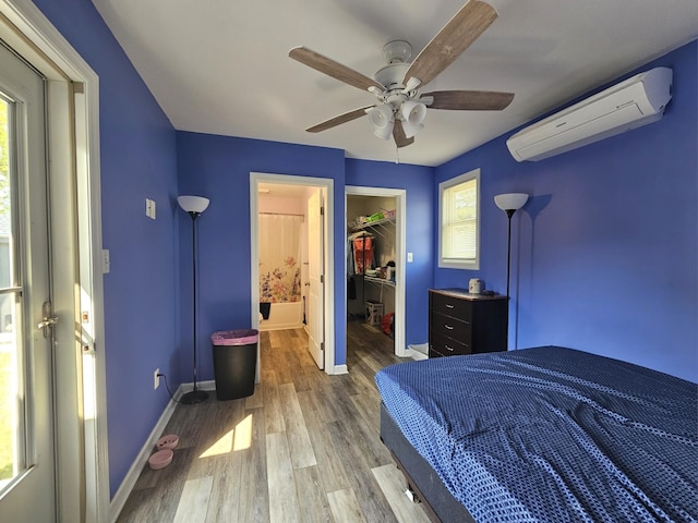 bedroom with a wall mounted AC, multiple windows, and wood finished floors