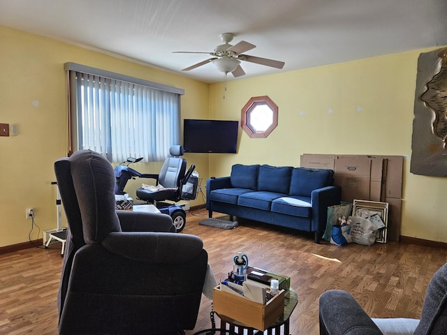 living room featuring baseboards, ceiling fan, and wood finished floors