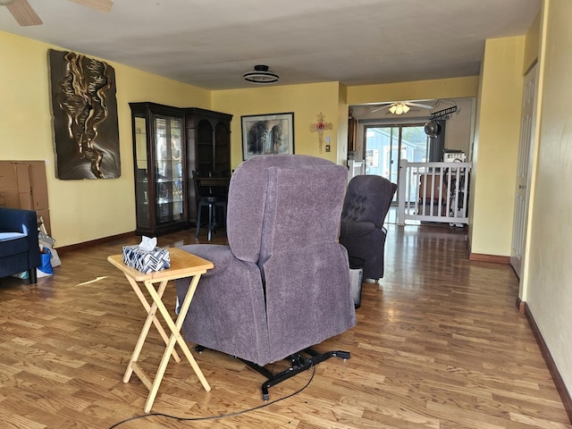 living room featuring a ceiling fan, baseboards, and wood finished floors