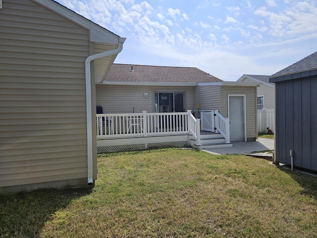 back of house featuring a lawn, a shingled roof, and a deck