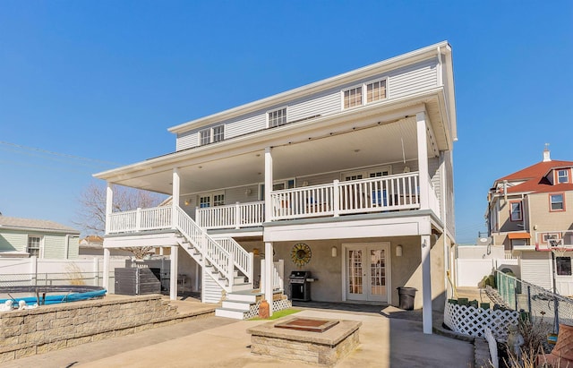 view of front of property with an outdoor fire pit, a patio, fence, french doors, and stucco siding