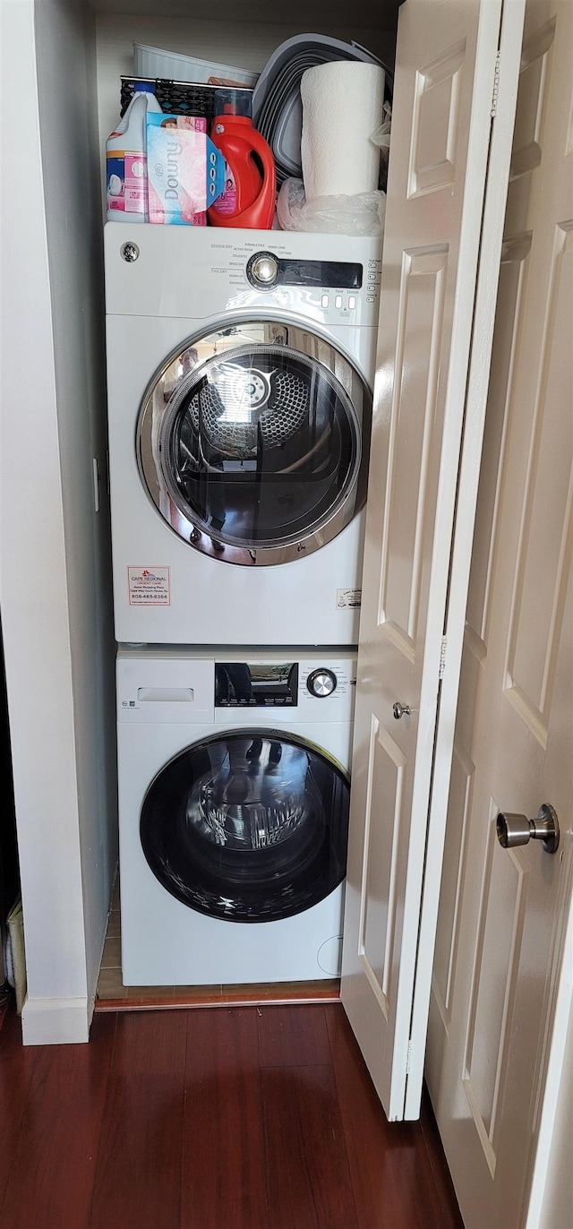 washroom featuring dark hardwood / wood-style flooring and stacked washer / drying machine