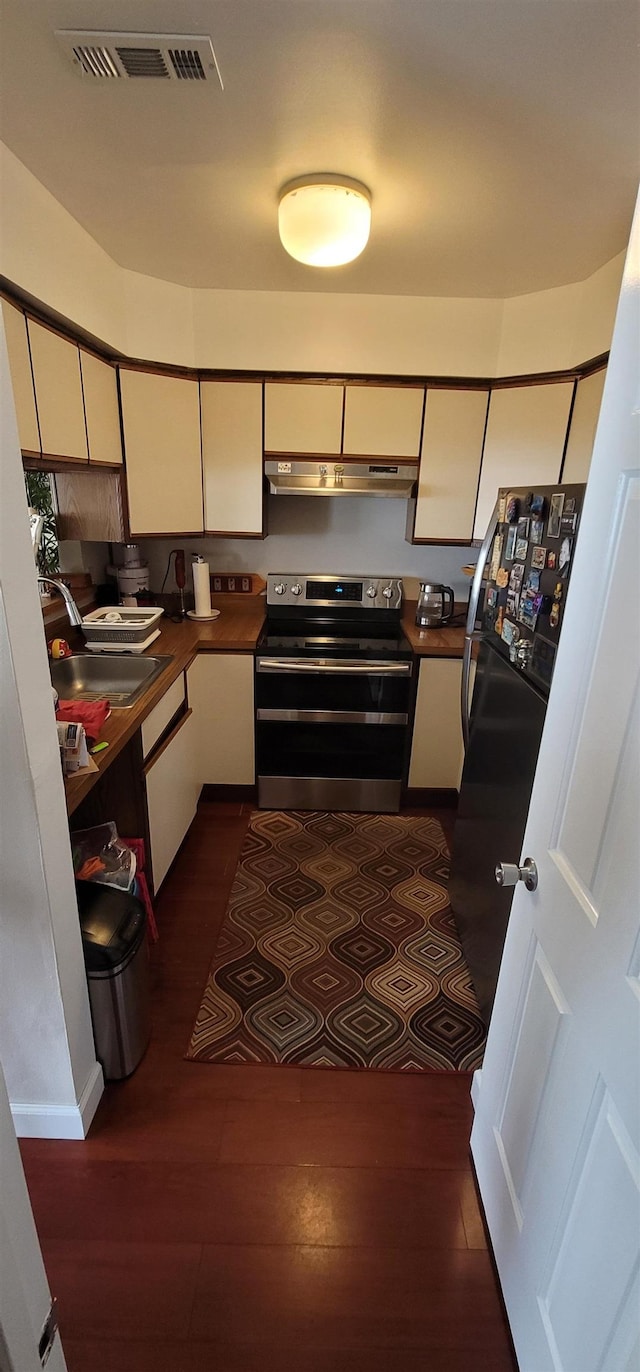 kitchen with stainless steel electric stove, dark hardwood / wood-style flooring, black refrigerator, and sink