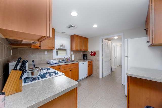 kitchen with decorative backsplash, light tile patterned floors, white appliances, and sink