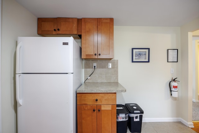 kitchen with backsplash, light tile patterned flooring, and white refrigerator