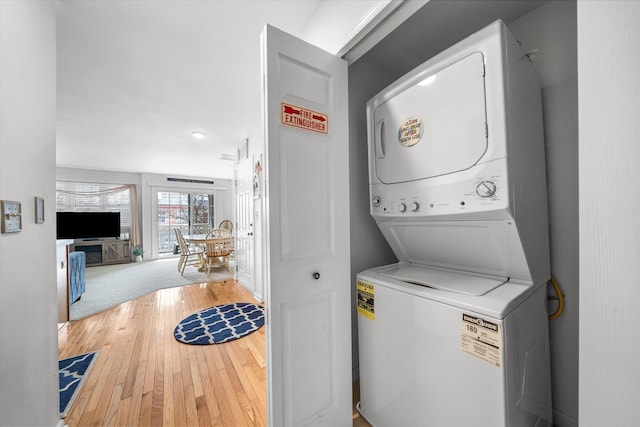 washroom featuring laundry area, wood-type flooring, and stacked washer and dryer