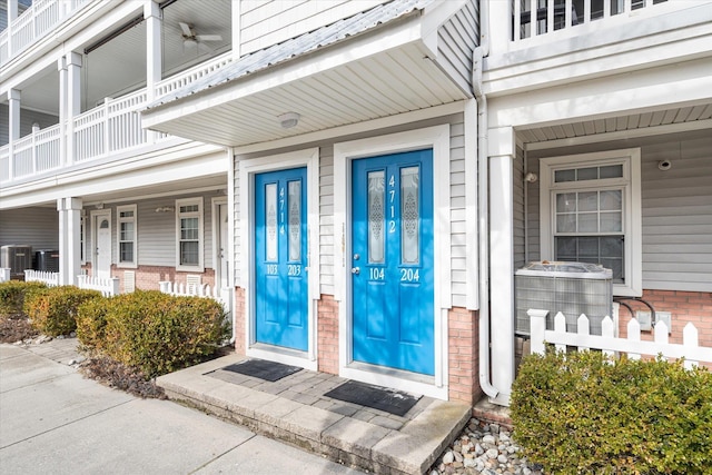 view of exterior entry with brick siding and central AC unit