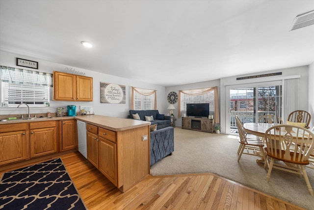 kitchen featuring visible vents, a peninsula, a sink, light countertops, and light wood-style floors