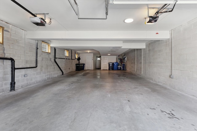 garage with a garage door opener and concrete block wall