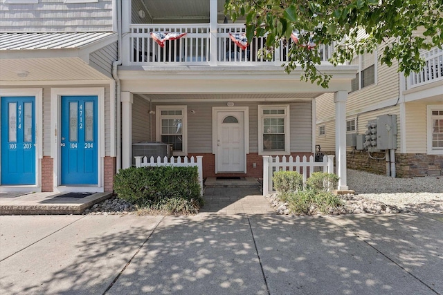 property entrance featuring central AC unit, brick siding, and covered porch