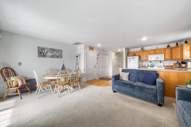 living room featuring recessed lighting, visible vents, and light carpet