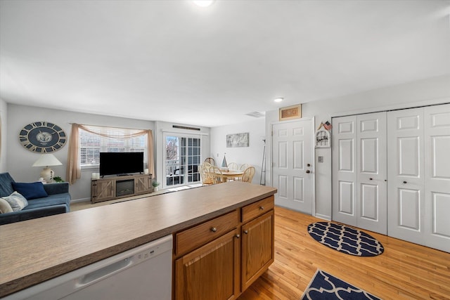 kitchen with visible vents, light wood-style flooring, open floor plan, brown cabinetry, and dishwasher