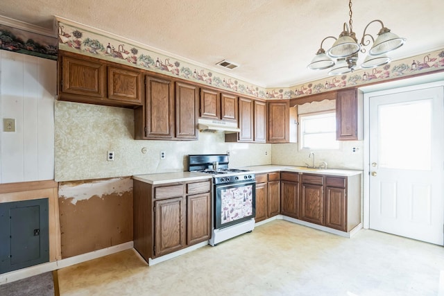 kitchen with sink, gas range, hanging light fixtures, a textured ceiling, and a notable chandelier