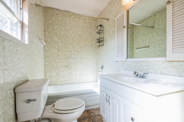 full bathroom featuring vanity, tiled shower / bath, tile walls, and toilet