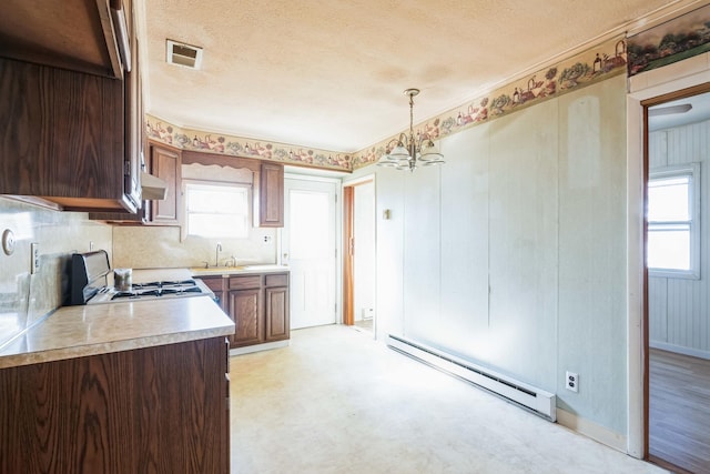 kitchen with sink, range, baseboard heating, hanging light fixtures, and a textured ceiling