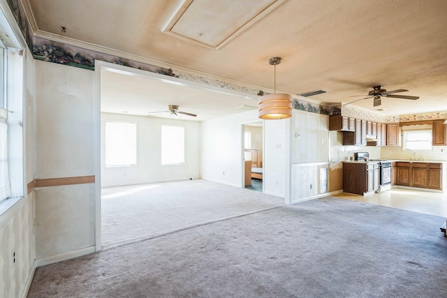 unfurnished living room with crown molding, sink, light carpet, and ceiling fan