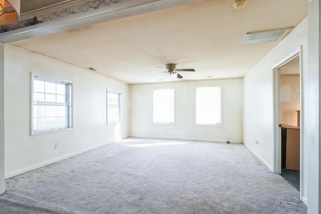 empty room featuring ceiling fan, light colored carpet, and a healthy amount of sunlight