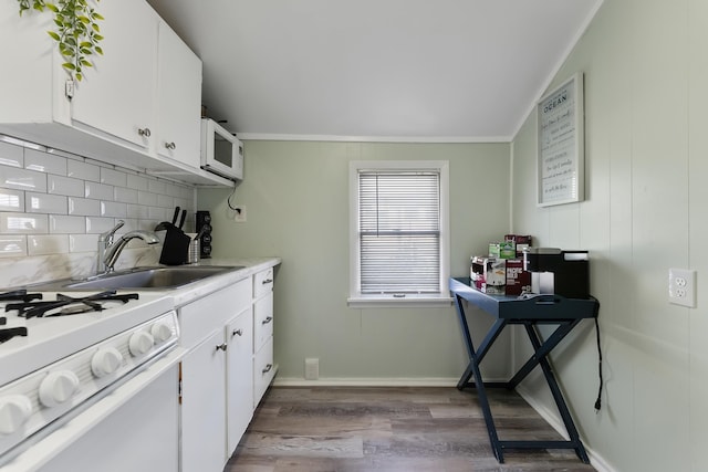 kitchen featuring sink, white appliances, tasteful backsplash, light hardwood / wood-style floors, and white cabinets