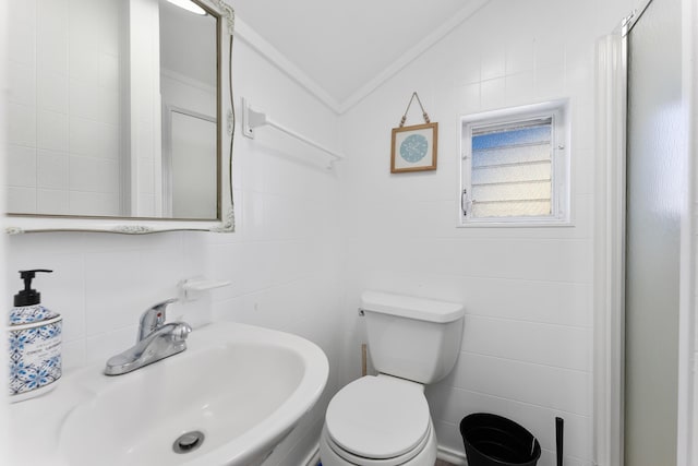 bathroom with lofted ceiling, toilet, sink, tasteful backsplash, and tile walls