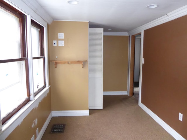 unfurnished room with light colored carpet and crown molding