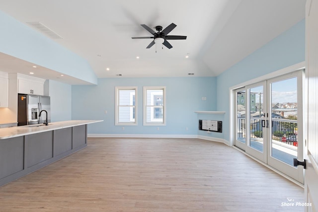 unfurnished living room featuring ceiling fan, french doors, a multi sided fireplace, light hardwood / wood-style flooring, and lofted ceiling