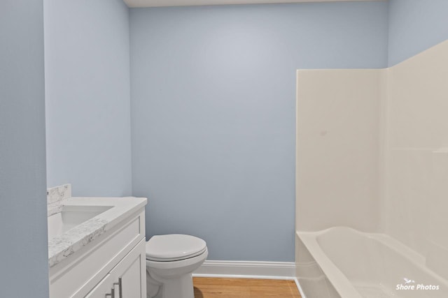 bathroom featuring a washtub, wood-type flooring, vanity, and toilet