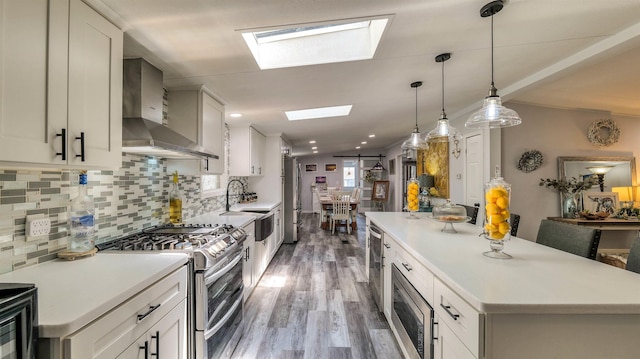 38 Kings Ln, Cape May Court House, NJ 08210 - kitchen featuring stainless steel appliances, wall chimney range hood, a skylight, light wood-style flooring, and light countertops
