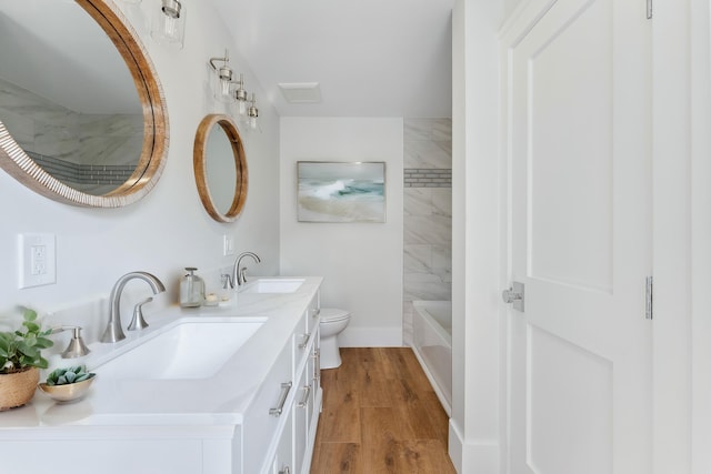 full bathroom featuring toilet, vanity, tiled shower / bath, and wood-type flooring