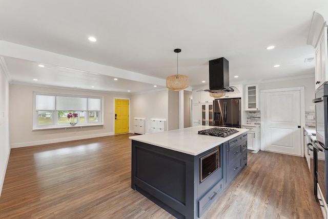 kitchen with white cabinetry, a center island, hanging light fixtures, island range hood, and appliances with stainless steel finishes