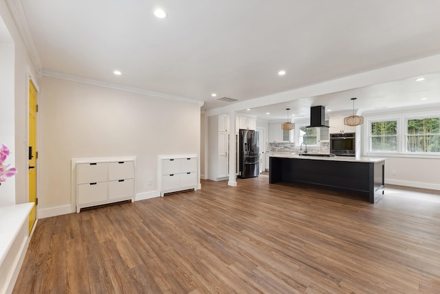 unfurnished living room with hardwood / wood-style floors, sink, and crown molding