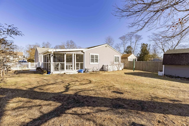 back of house with an outbuilding, a storage shed, fence, a sunroom, and a lawn