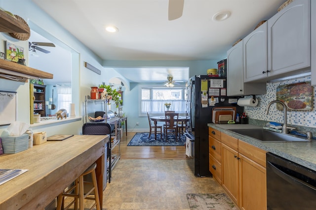 kitchen featuring a sink, a ceiling fan, baseboards, black appliances, and tasteful backsplash