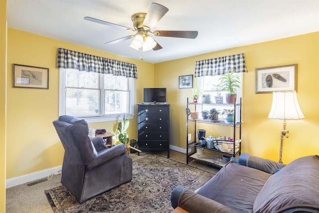 living area with carpet floors, baseboards, visible vents, and a ceiling fan