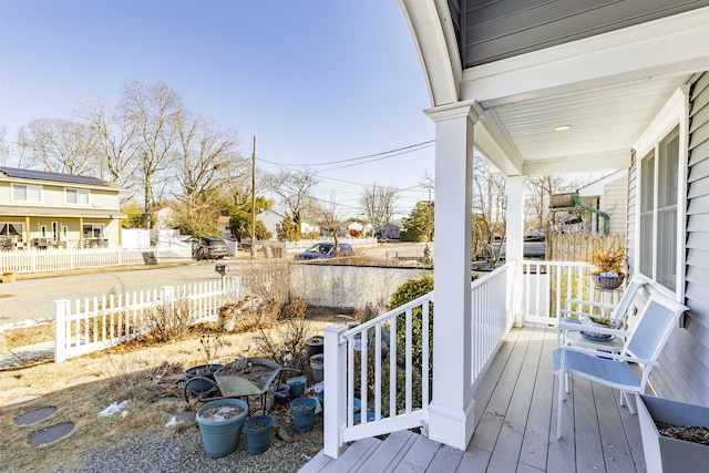 wooden terrace featuring a residential view, fence, and a porch