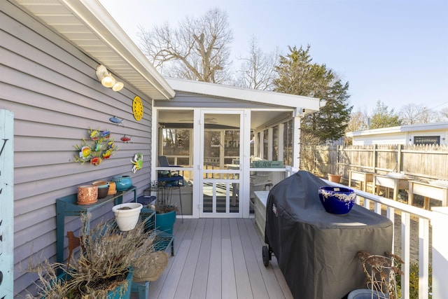 wooden terrace with a sunroom, fence, and grilling area