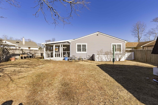 back of house with a sunroom, a fenced backyard, and a yard