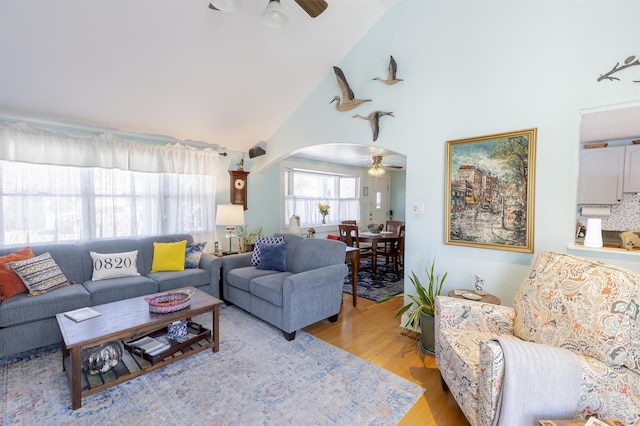 living area featuring ceiling fan, high vaulted ceiling, arched walkways, and light wood-style floors