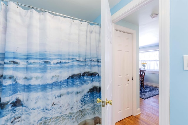 bathroom with a shower with curtain, baseboards, and wood finished floors