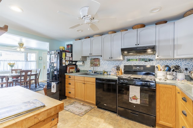 kitchen with decorative backsplash, under cabinet range hood, light countertops, black appliances, and a sink