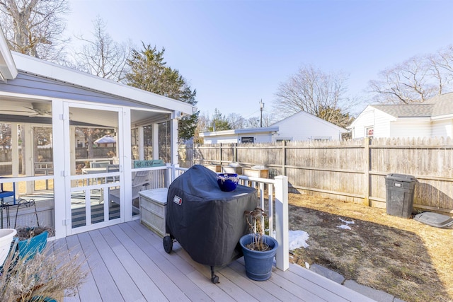 wooden terrace featuring grilling area, a fenced backyard, and a sunroom