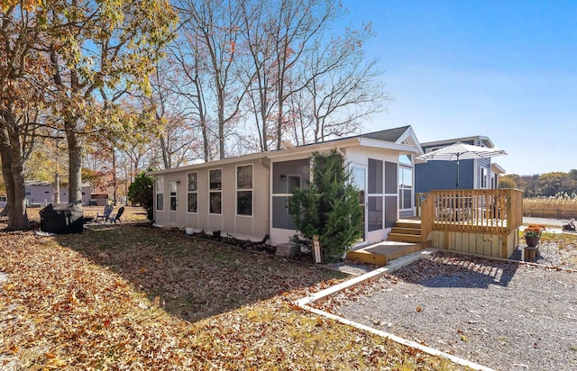 view of side of home featuring a sunroom and a wooden deck